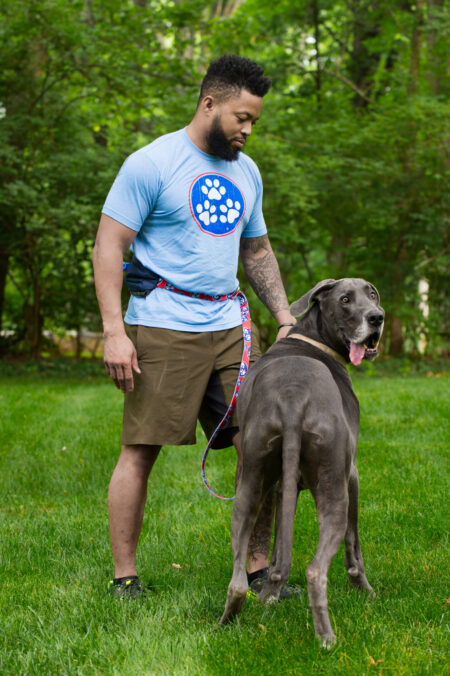 A man and his dog are standing in the grass.