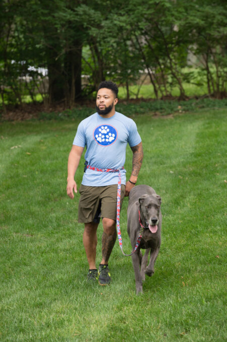 A man walking his dog in the grass.