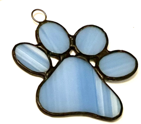 A blue stained glass paw print hanging from a gold chain.