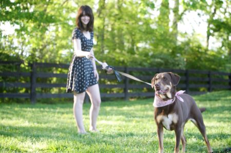 A woman is walking her dog on a leash.