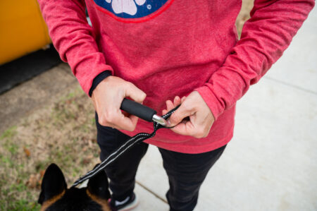 A person holding scissors and cutting something on the ground.