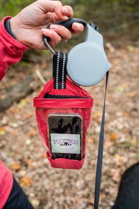 A person holding up a phone case with headphones hanging from it.